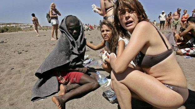 Turistas ayudan a un inmigrante en una playa de las islas Canarias
